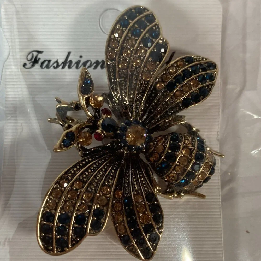 Rhinestone bee brooch pin with black and amber crystals, set in gold tone metal.